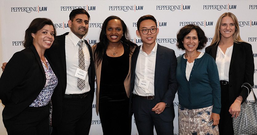 six people standing in front of white pepperdine law step and repeat sign