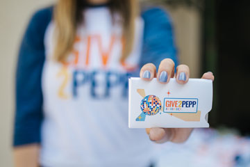 girl with blue nails holding out a give2pepp card
