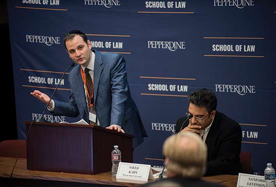 Professor Michael Helfand speaking at a podium in front of a blue School of Law Sign at a Nootbaar event
