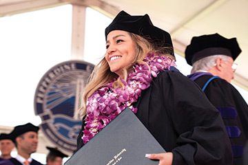 Female law graduate clutching her diploma wearing a flower lei