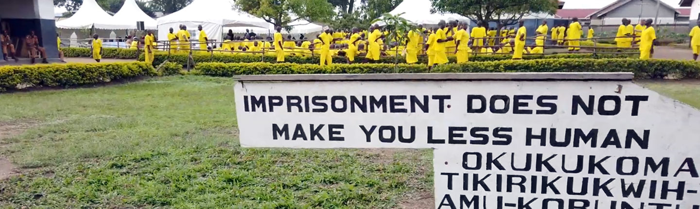 Sign from a Ugandan prison with inmates in the background