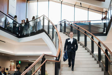a male professional descending the stairs holding a briefcase