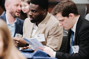 three male students looking over a brochure at a School of Law event