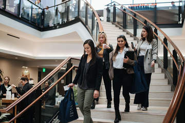 Four female JD students walk down the stairs in the atrium