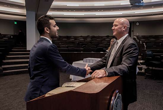 Law school student shaking hands with faculty member in auditorium