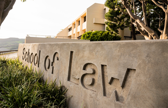 Caruso School of Law sign outside lit up by sunset