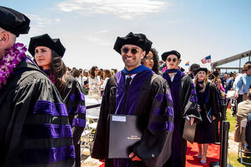 a line of graduates holding their diplomas at graduation