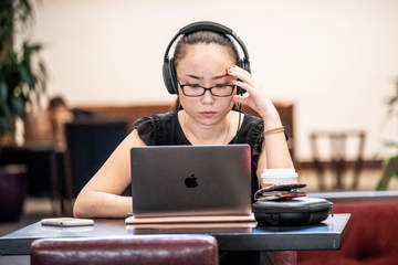 a female student in headphones working on a laptop at the School of Law