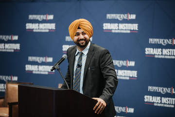 Professor Singh stands at a podium for a Straus Institute event