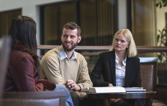 three students sitting around a table discussing mediation