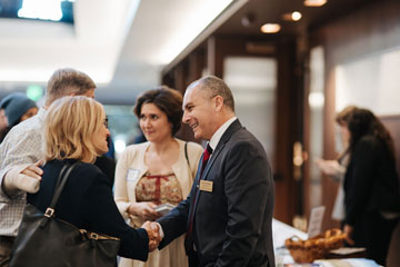 a man and a woman shaking hands at a Straus Institute event at the School of Law
