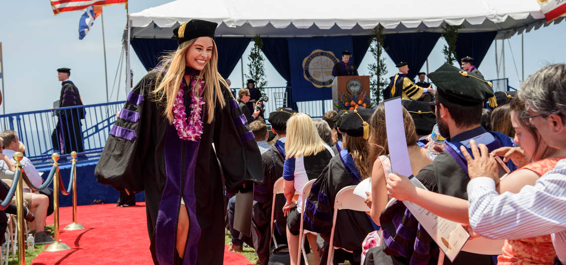 female student walking down the red carpet at graduation