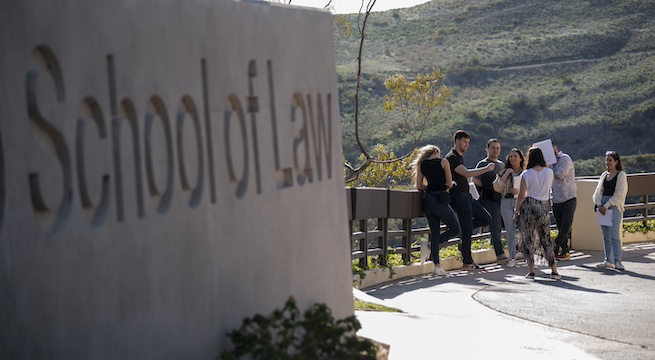 pepperdine caruso law students standing by the pepperdine school of law sign