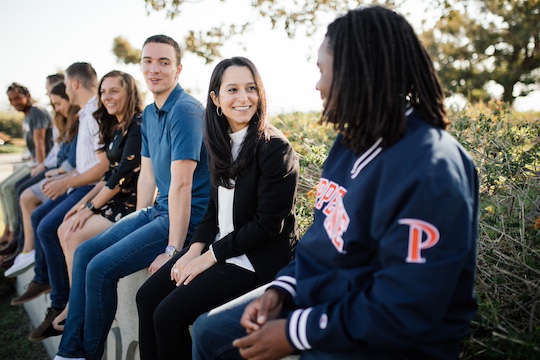 pepperdine law students sitting on top of the caruso school of law sign