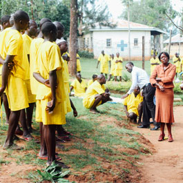 Inmates dressed in yellow speak outside in a Uganda prison