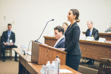 A female student standing up at a podium at a moot court competition 