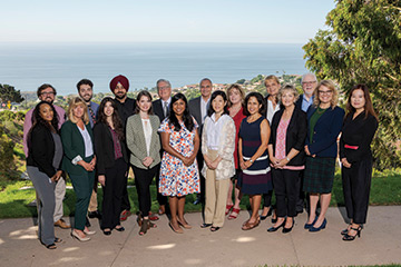 The Straus Institute staff standing for a group photo in front of the ocean at the School of Law