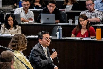 Professor David Han holding a microphone and addressing students in the Caruso auditorium at the school of law
