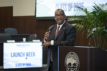 Judge Andre Birotte speaking at a podium in front of a Launch Week sign at Pepperdine Caruso School of Law