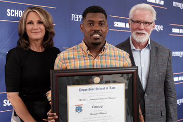 Rex and Carroll Parris stand with a student who is holding a framed parris award for courage at a ceremony