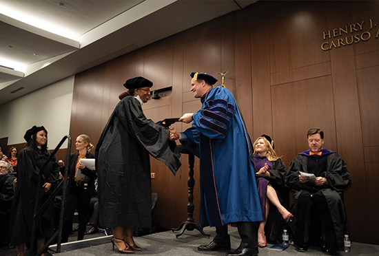 a woman receivnig a degree and shakinig hands with Pepperdine President Jim Gash