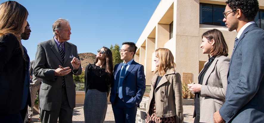The entire Straus staff standing outside for a group photo with the Pacific ocean visible in the background