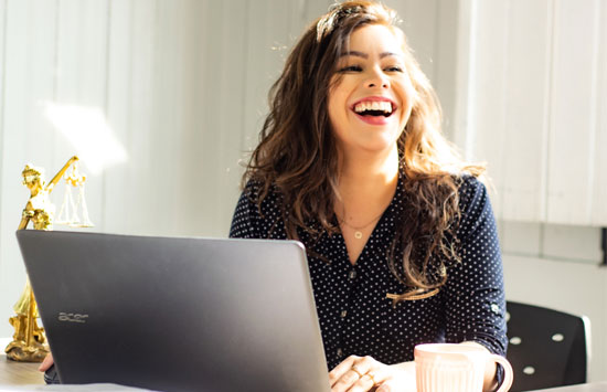woman laughing sitting in front of a laptop