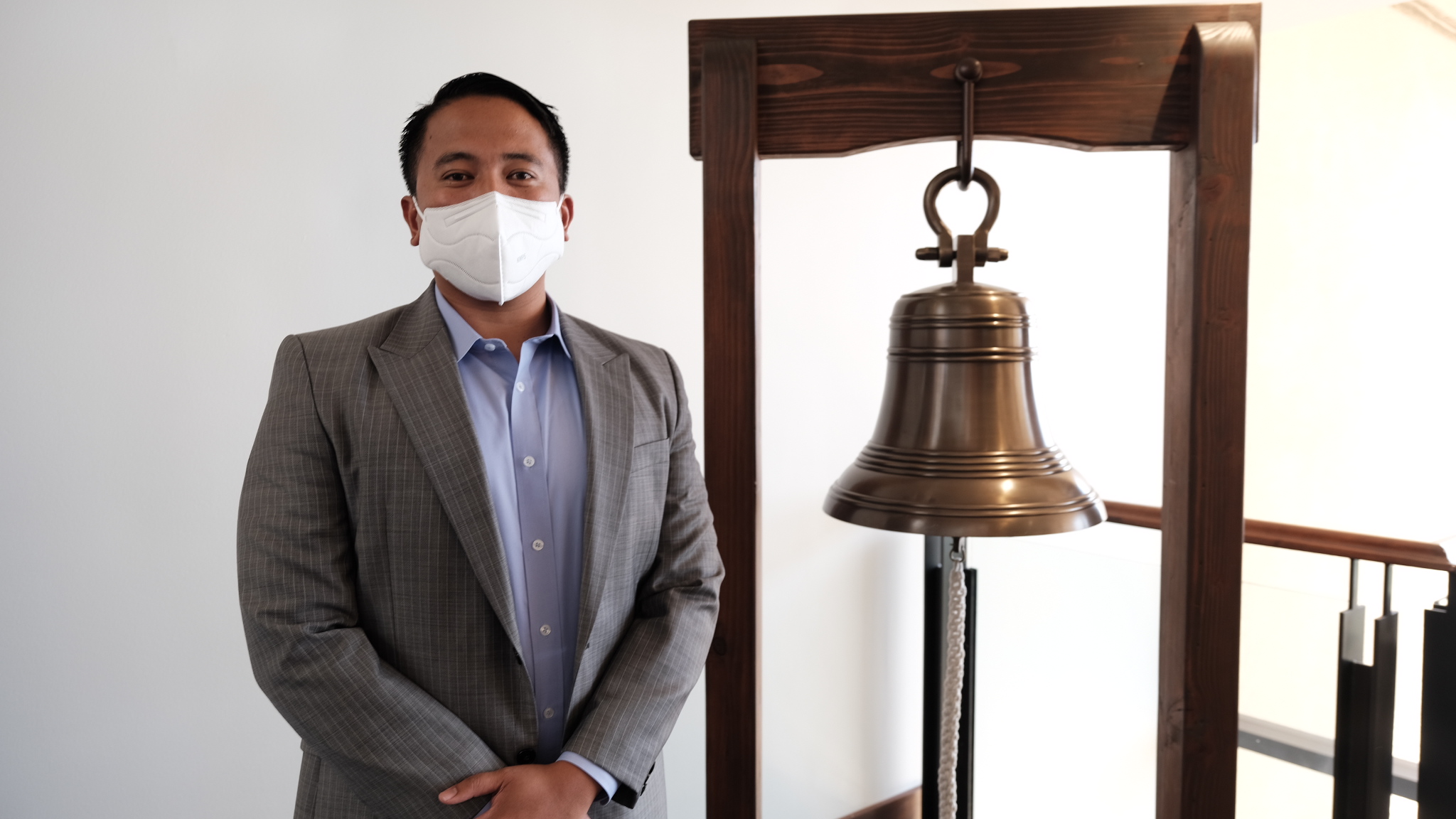 Joseph Castro stands next to the jobs bell