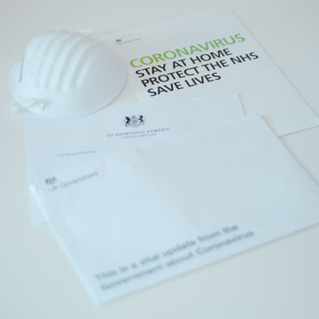 Coronavirus informational papers next to a white face mask