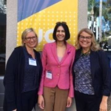 Three clinical law professors in front of clinical conference banner