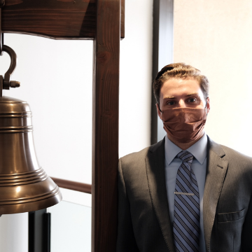 Jared Antman stands next to the bell