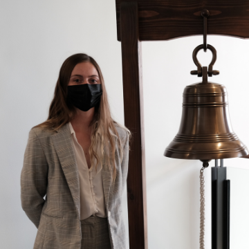 Katelyn Dykhouse stands next to the jobs bell