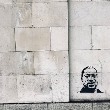 A concrete wall with a spray-painted image of George Floyd