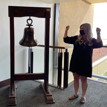 Tatum Lowe next to the bell