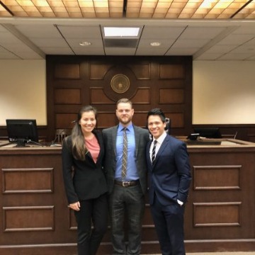 Three student winners in trial courtroom