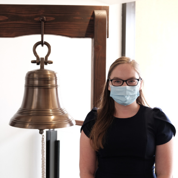 Rebecca Voth stands next to the jobs bell