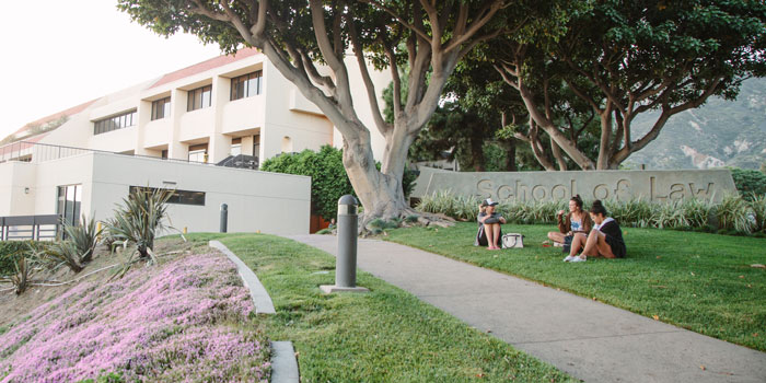 students sitting in front of the School of Law sign